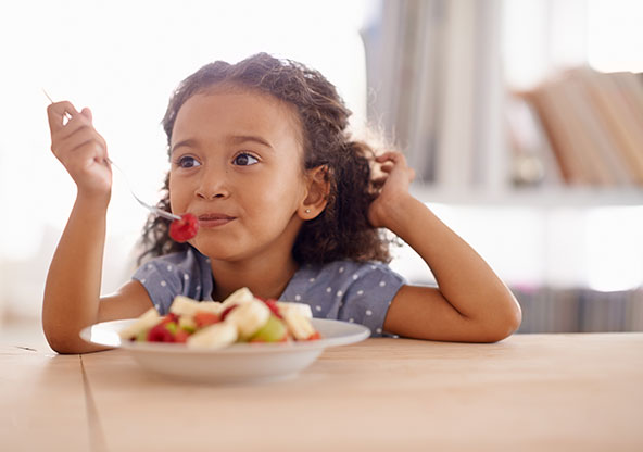 Little girl eating fruit