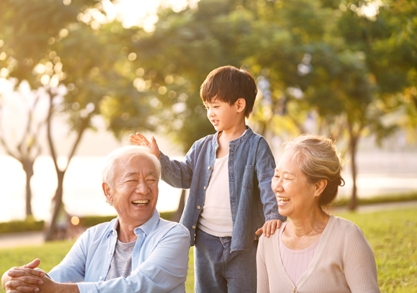 Two Asian grandparents with their grandson outside